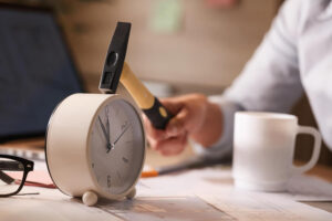close-up-businesswoman-hitting-clock-her-desk-while-working-office (1)