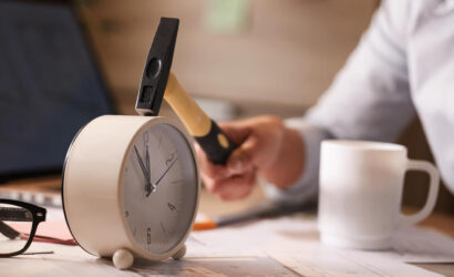 close-up-businesswoman-hitting-clock-her-desk-while-working-office (1)